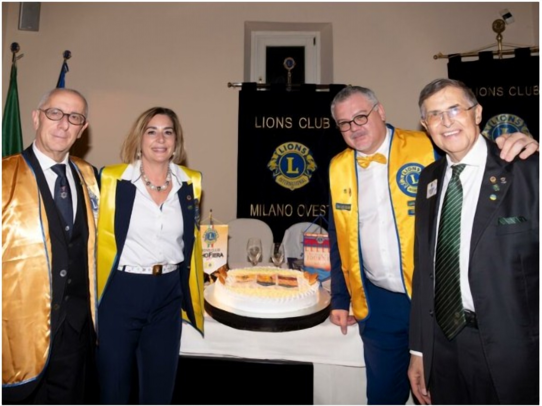 Il taglio della torta alla Charter Night del Lions Club Milano Ovest, davanti al labaro del Club