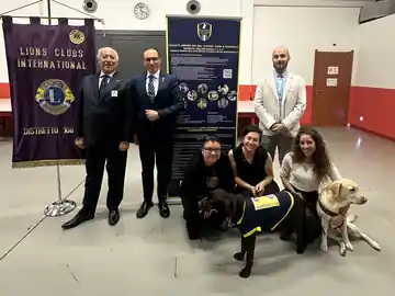 Soci e volontari con i cani sotto il labaro del Distretto 108