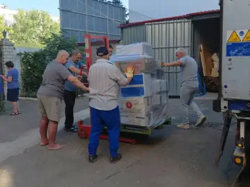 Volontari scaricano un bancale con il transpallet